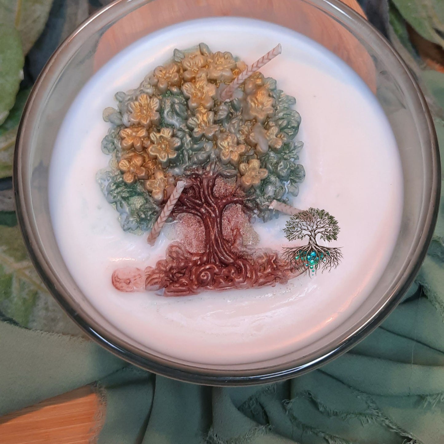 Decorative tree design on a white surface with a metallic rim, placed on a green fabric background.