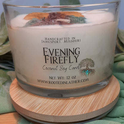 Coconut soy candle labeled 'Evening Firefly' on a wooden coaster with a green fabric background.