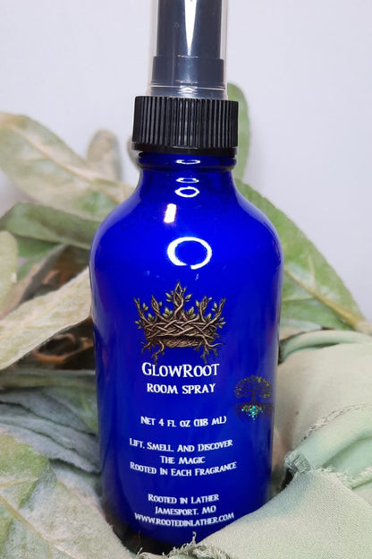 Blue room spray bottle with a black cap on a green leafy background