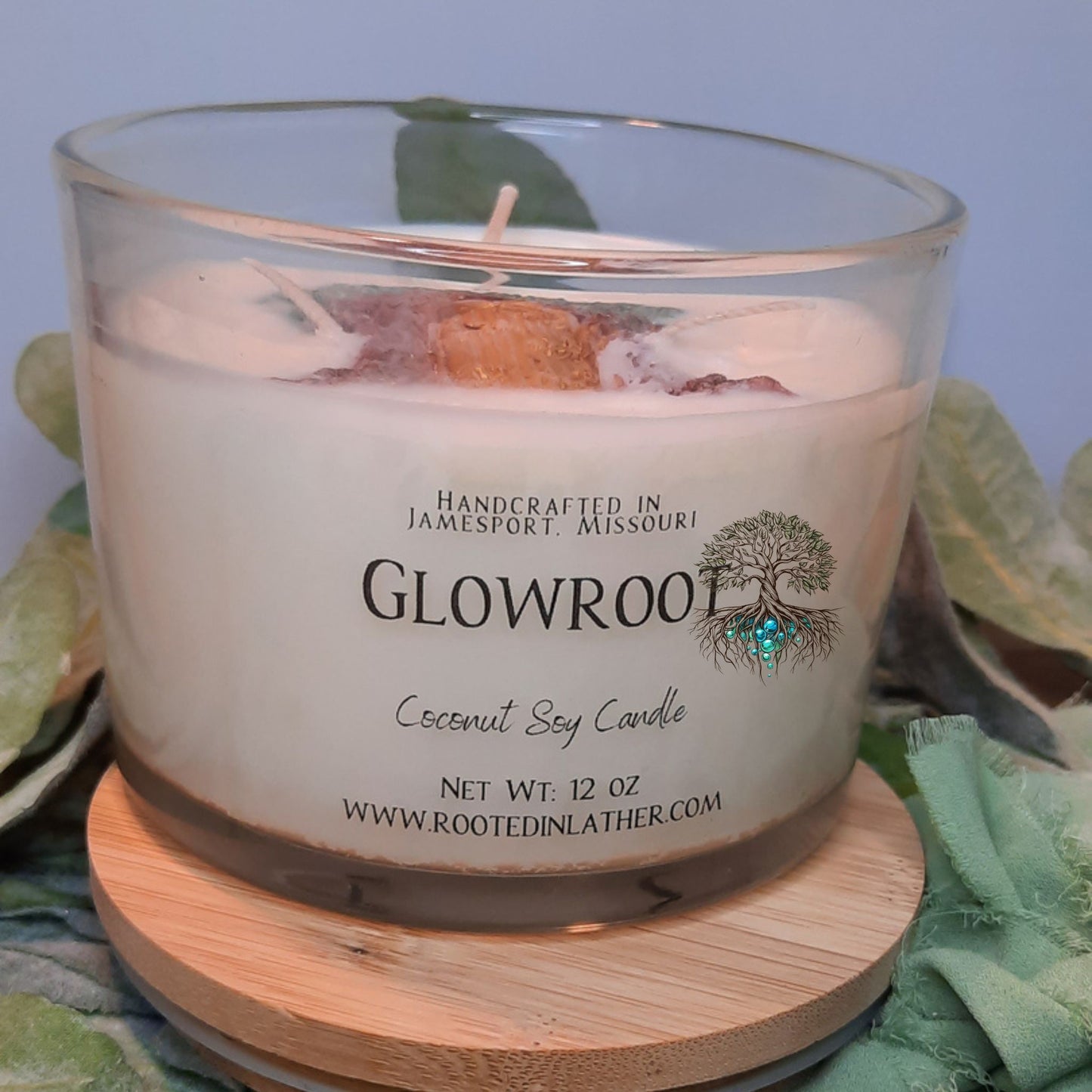 Glowroot coconut soy candle with a wooden coaster on a green fabric background