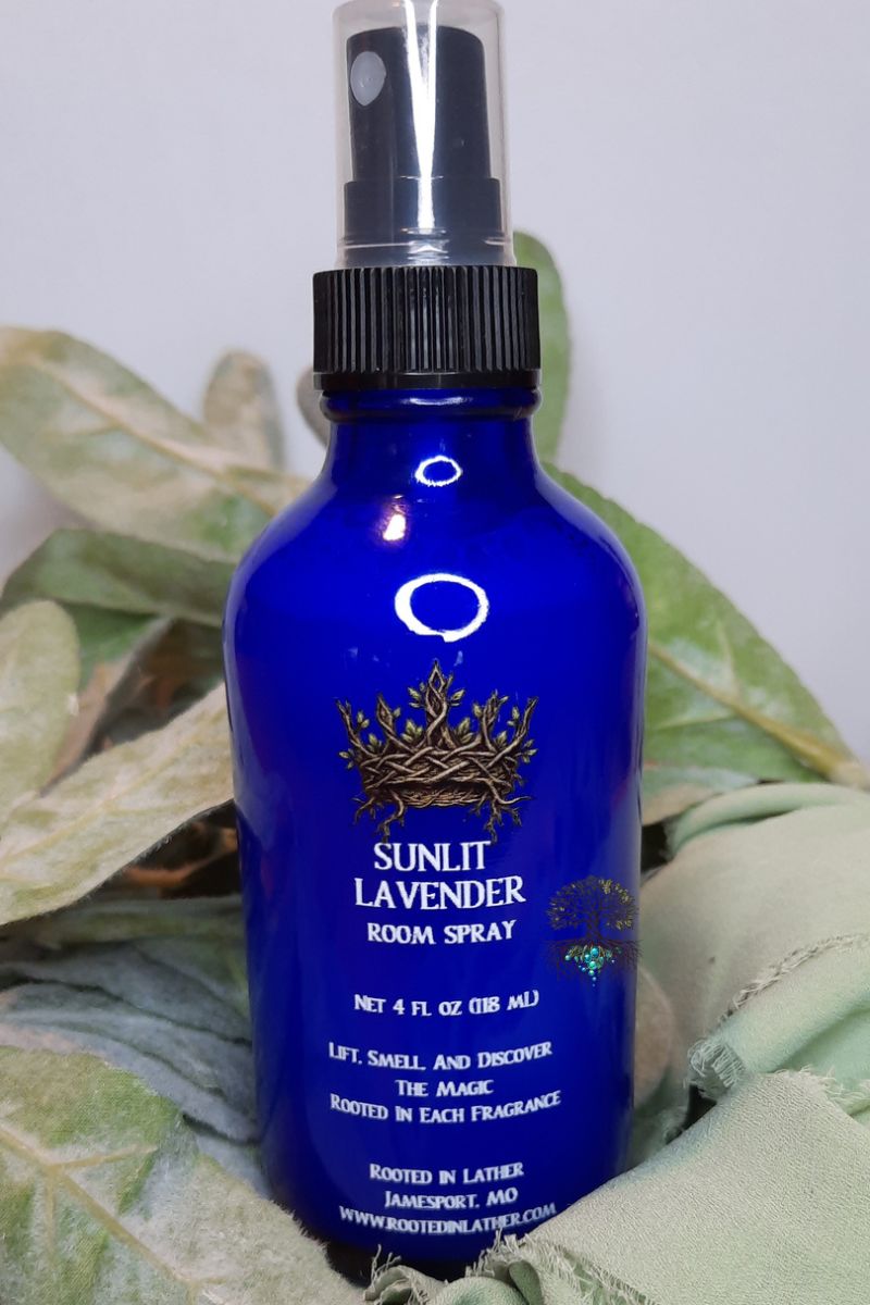 Blue room spray bottle labeled 'Sunlit Lavender' on a leafy background