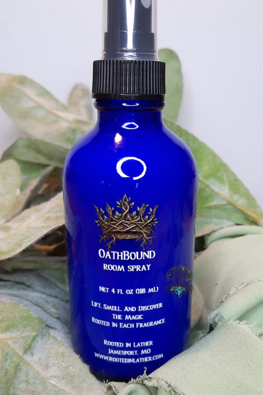Blue room spray bottle labeled 'Oathbound' on a green leafy background