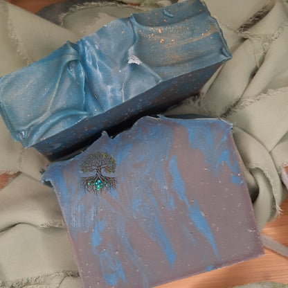 Two soap bars with blue and grey design on a textured surface