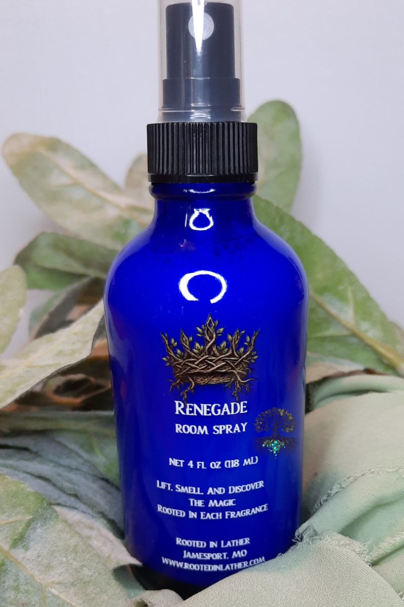 Blue room spray bottle with black nozzle on a leafy background