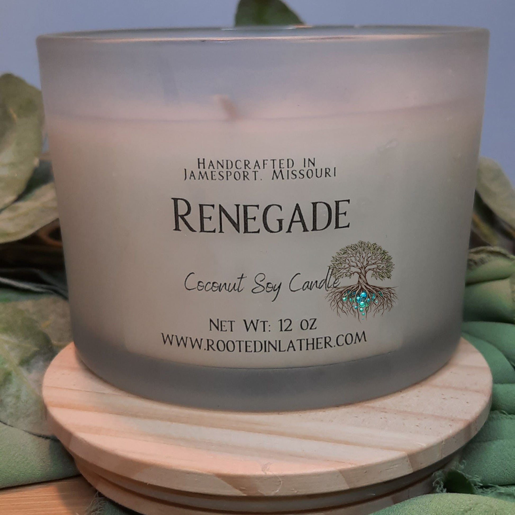 Coconut soy candle labeled 'Renegade' with branding details on a wooden coaster.
