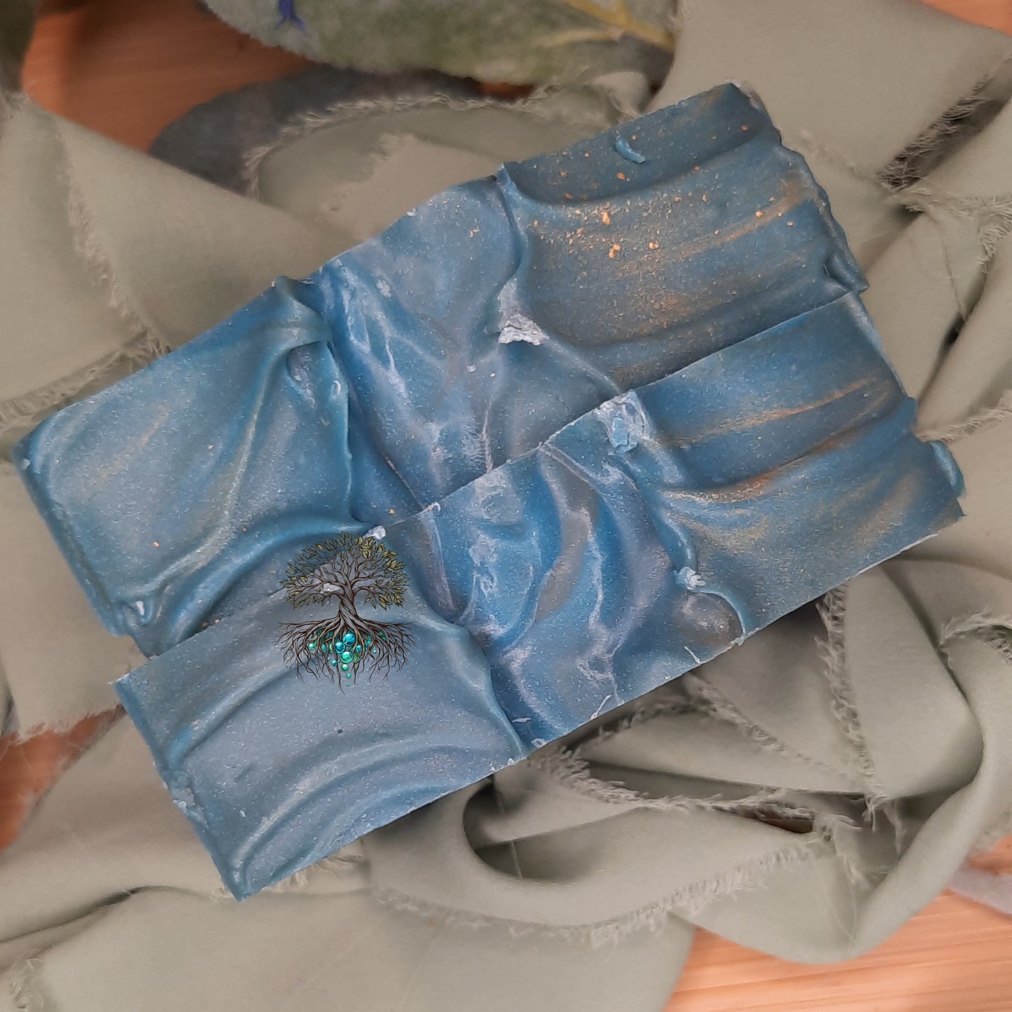 Blue marbled soap bar with a tree design on a gray surface