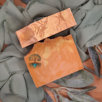 Two soap bars with tree designs on a textured surface