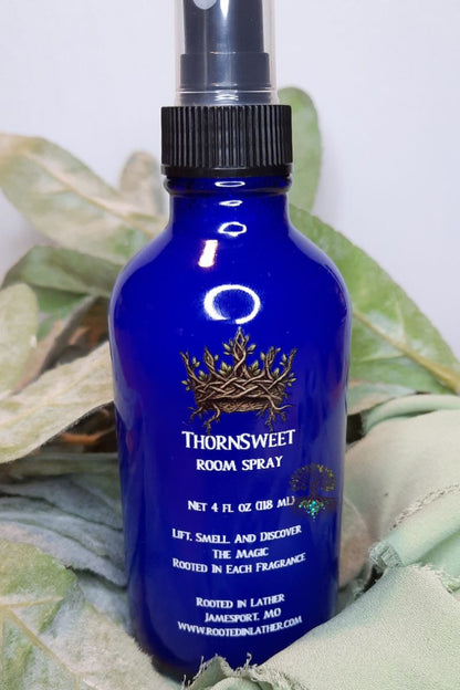 Blue room spray bottle with brand logo on a leafy background