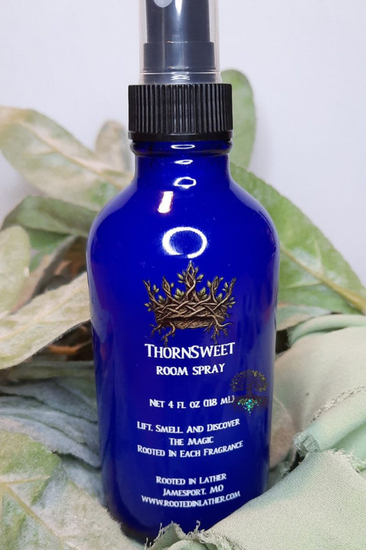 Blue room spray bottle with brand logo on a leafy background