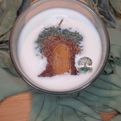 Decorative candle with tree and door design on a green leafy background
